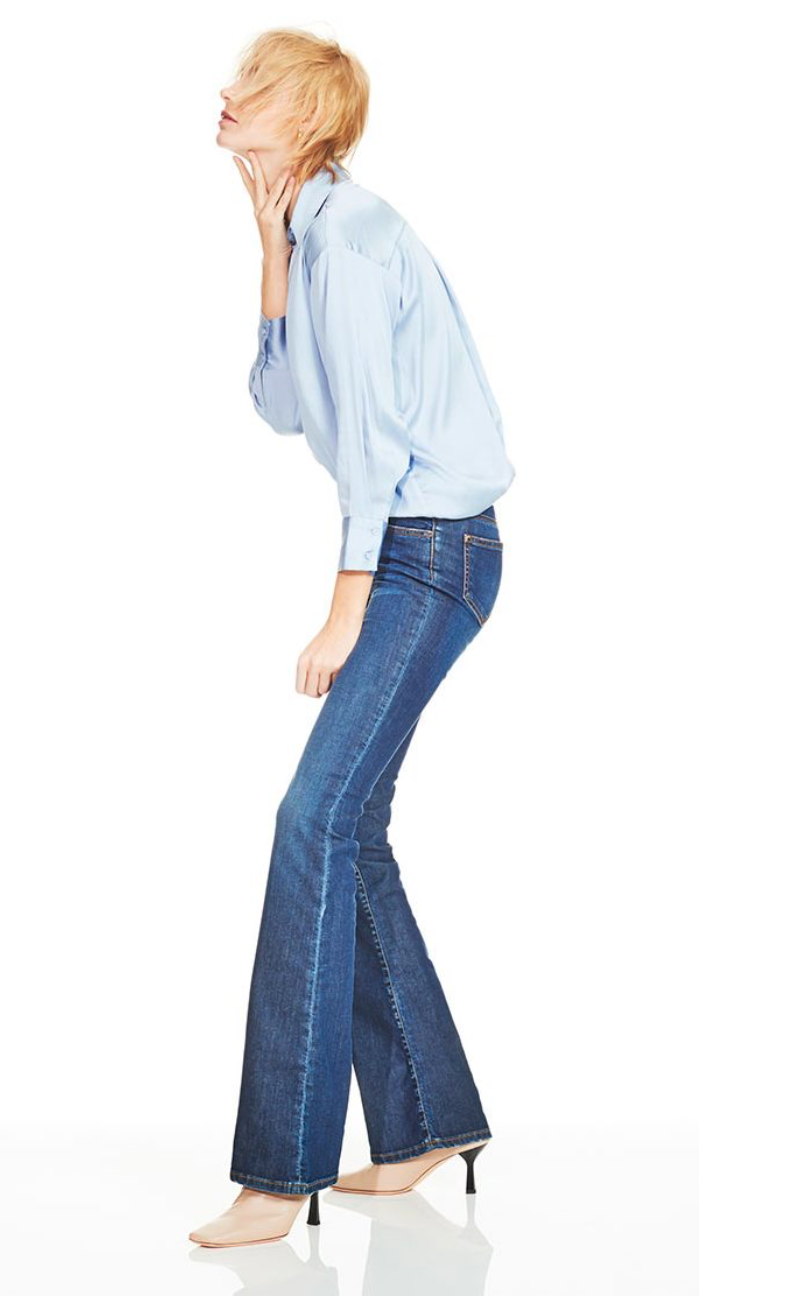 Modella con jeans e camicia azzurra, fotografata su fondo bianco per contenuti e-commerce di abbigliamento donna.