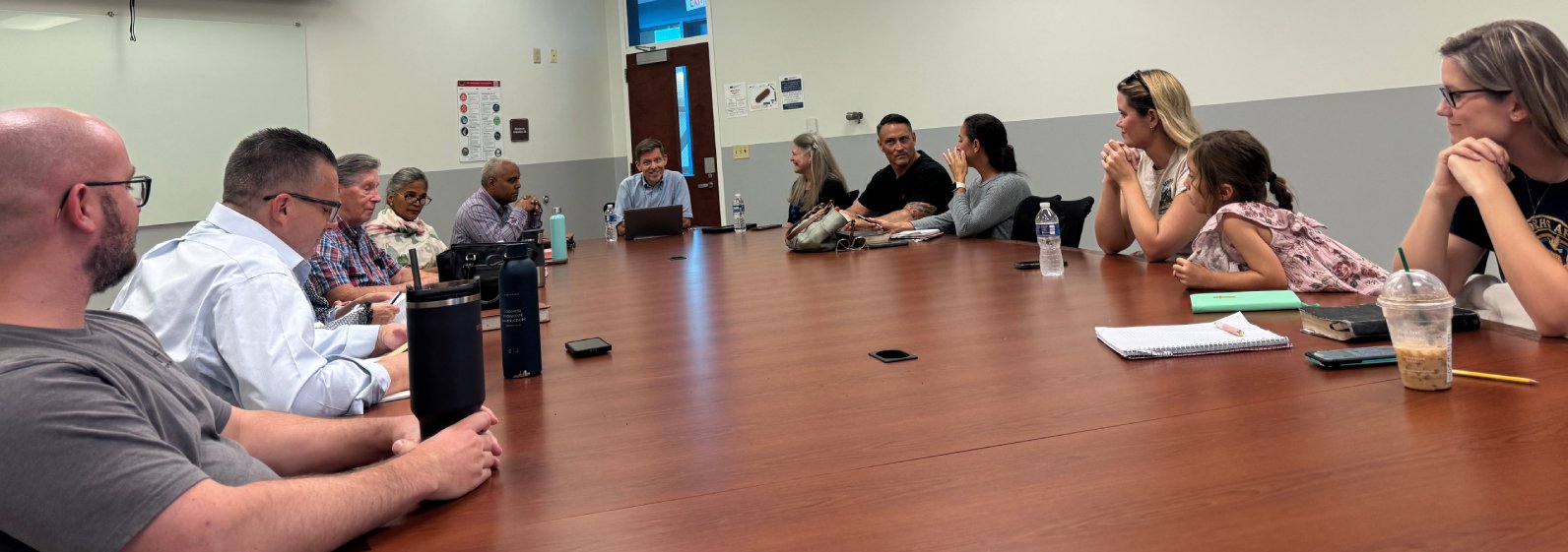 People sitting around a large conference table in a meeting room.