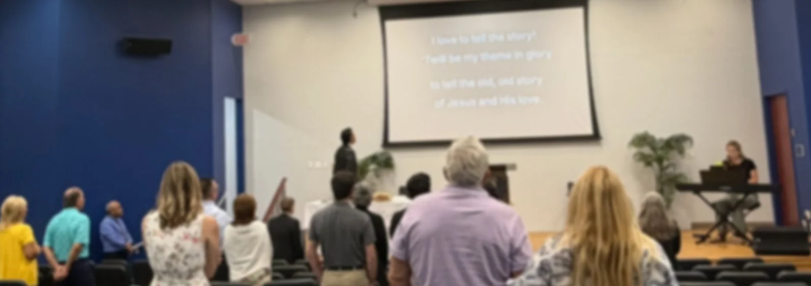 People attending a church service with a screen displaying lyrics