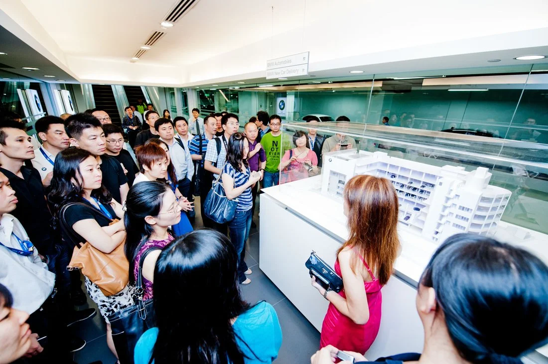 A group of people attending a presentation of an architectural model at a modern building.