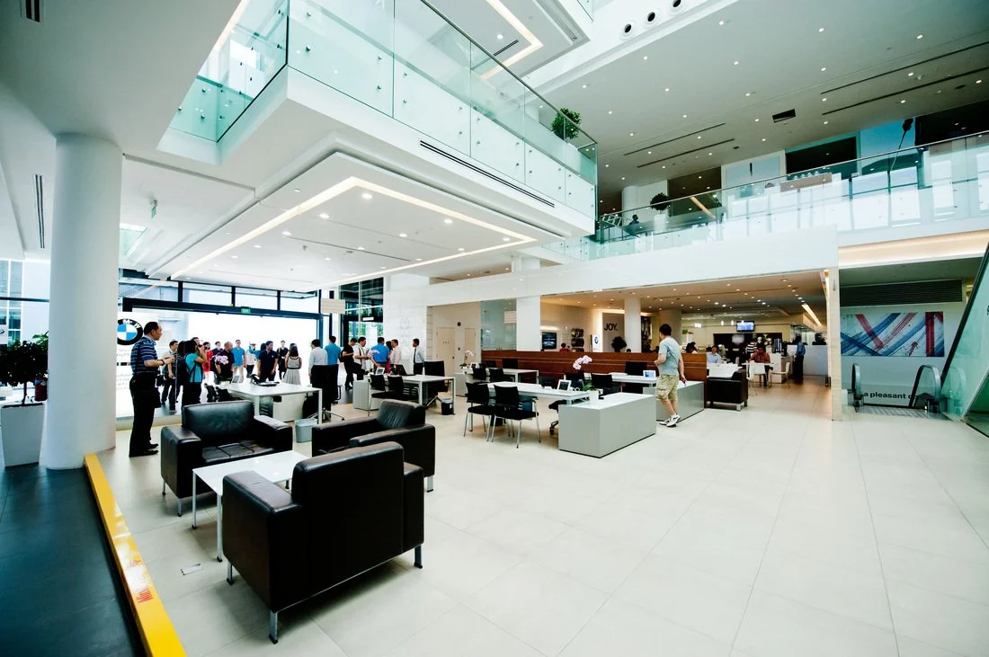 Interior of a modern car dealership showroom with people and seating area.