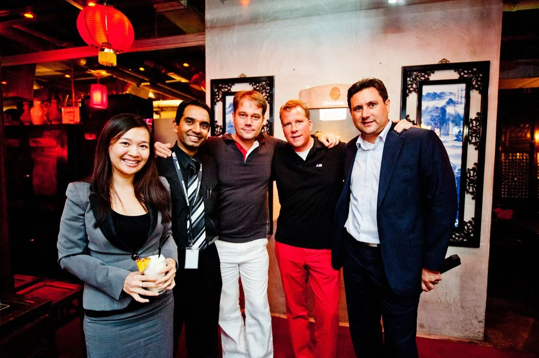 Group of five people at an Asian-themed restaurant or event, smiling and posing for a photo, with red lanterns and traditional artwork in the background.