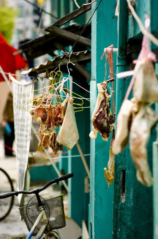 Dried meat pieces hanging on clotheslines outside a building