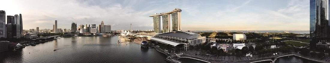 Panoramic view of Marina Bay Sands hotel and Singapore skyline, including waterfront, boats, and city buildings.