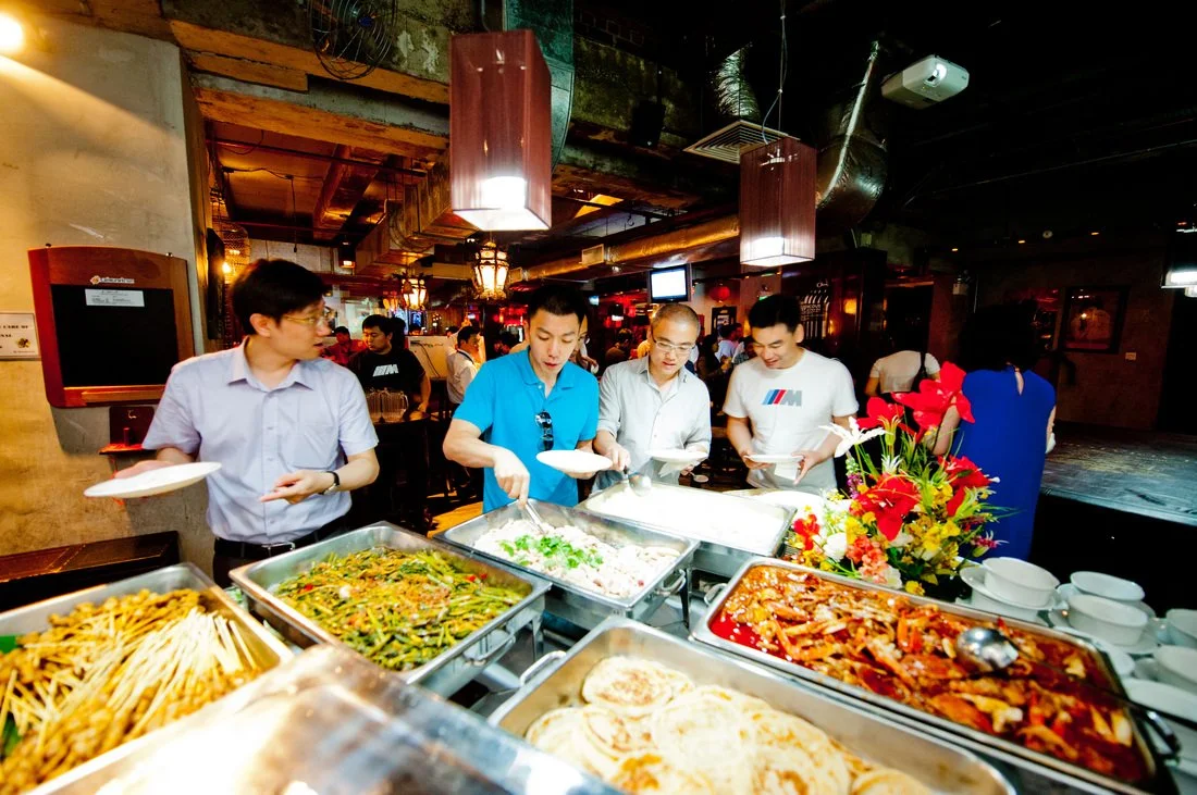 People serving themselves food at a buffet in a restaurant