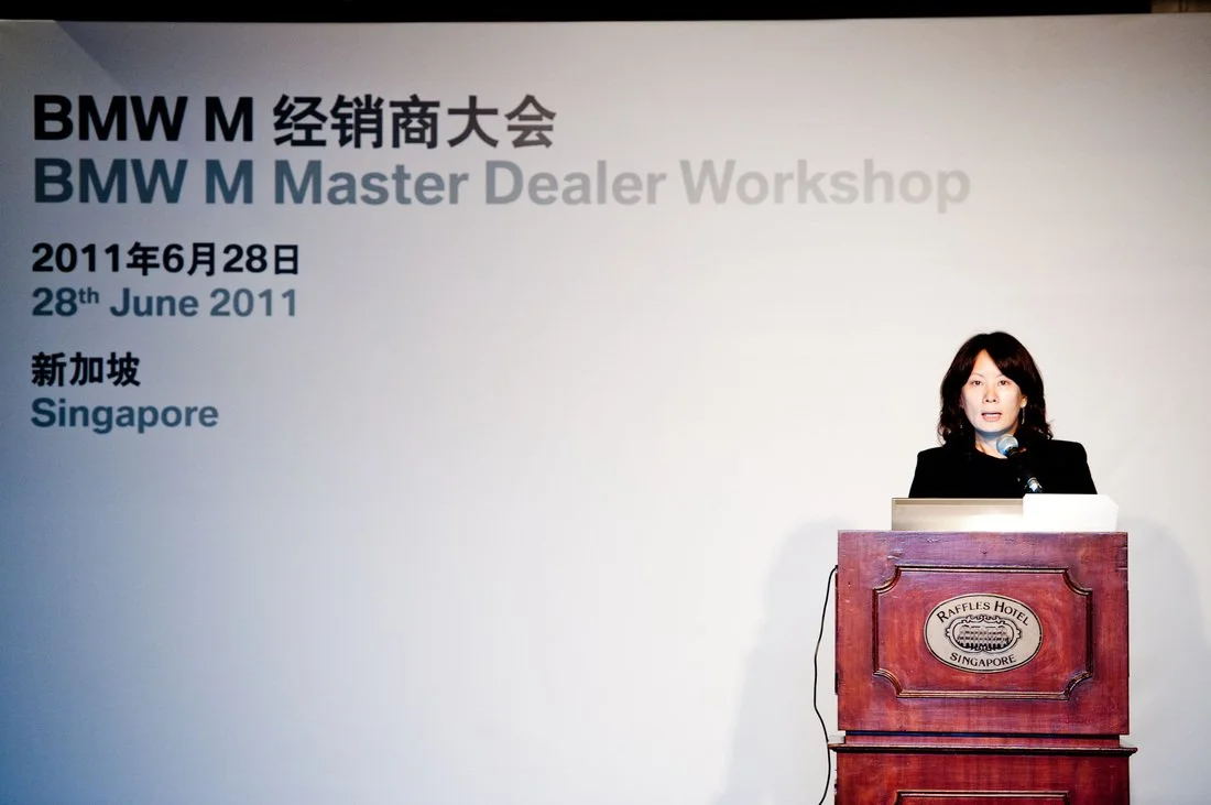 A woman speaking at a podium during a BMW Master Dealer Workshop on June 28, 2011, at Raffles Hotel in Singapore.
