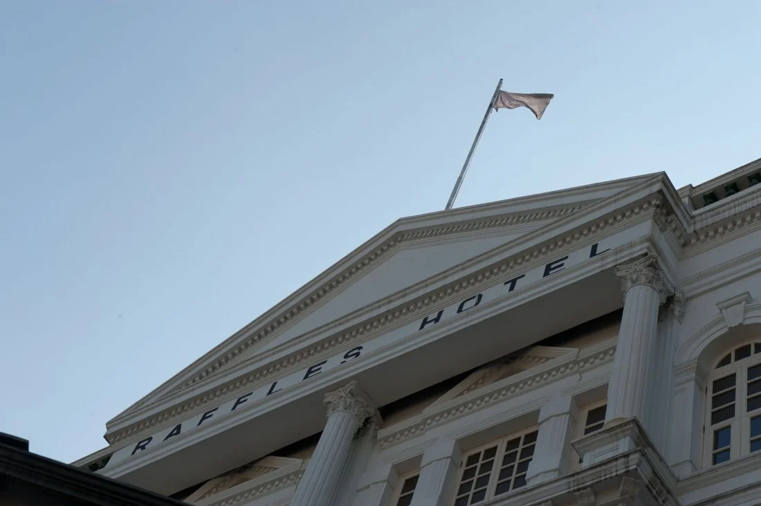 Exterior view of a historic hotel building with classical columns and a flag on top