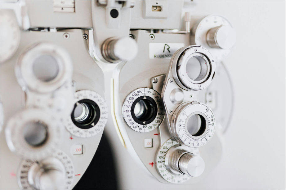 Close-up of phoropter with multiple dials and lenses used for eye exams at an optometrist's office.