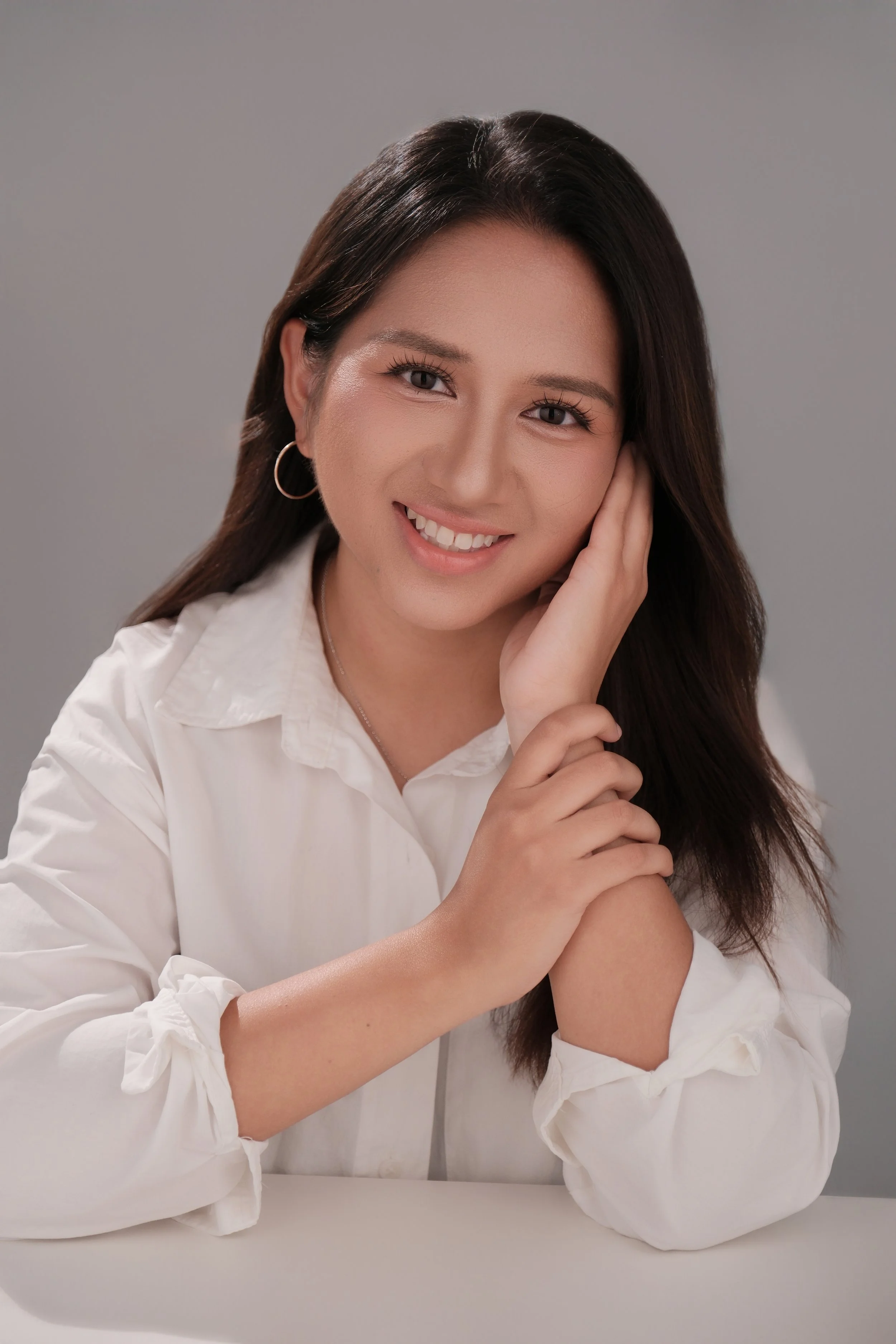 A professionally-dressed woman wearing a white shirt, smiling