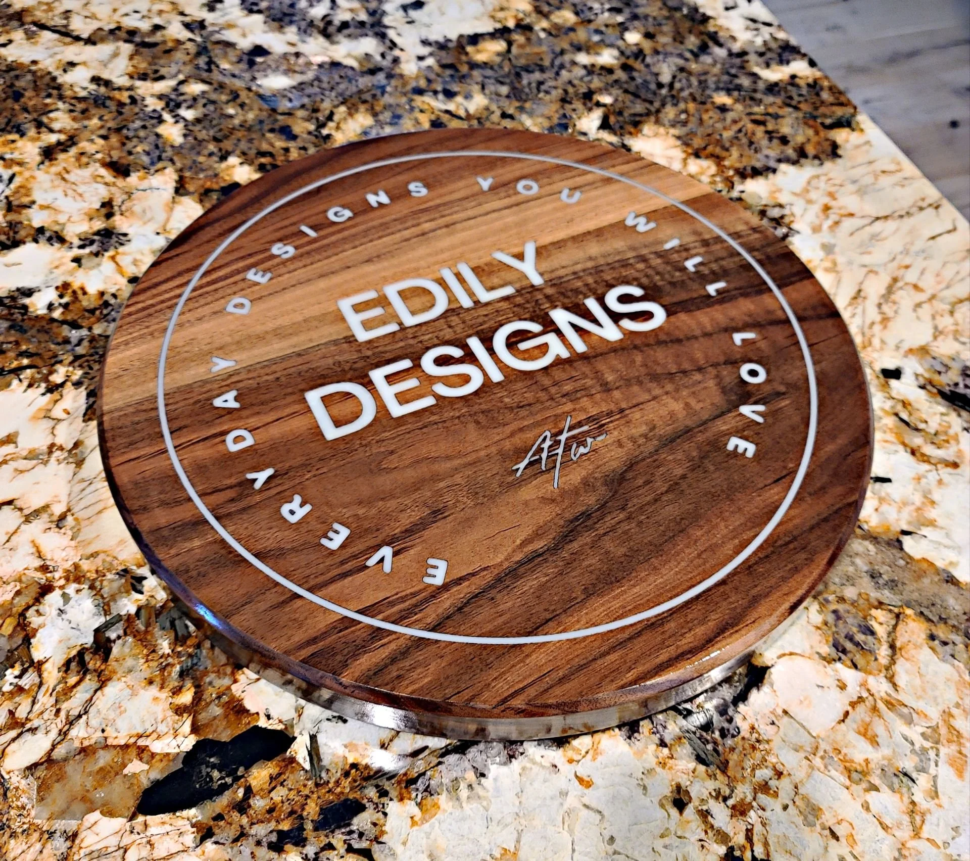 Round wooden clock with white letters on a granite countertop.