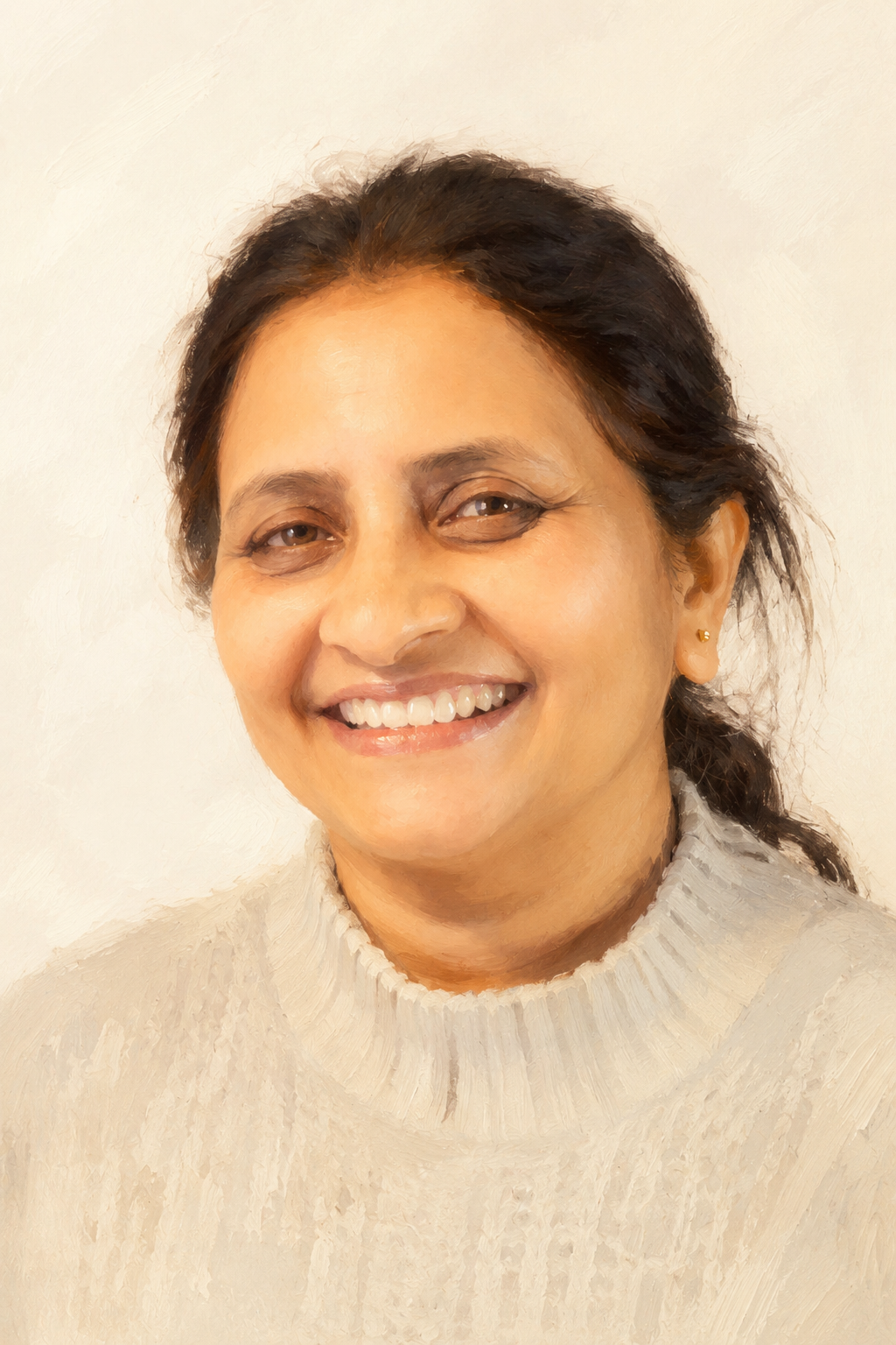A woman with dark hair, wearing a light-colored sweater, smiling against a plain background.