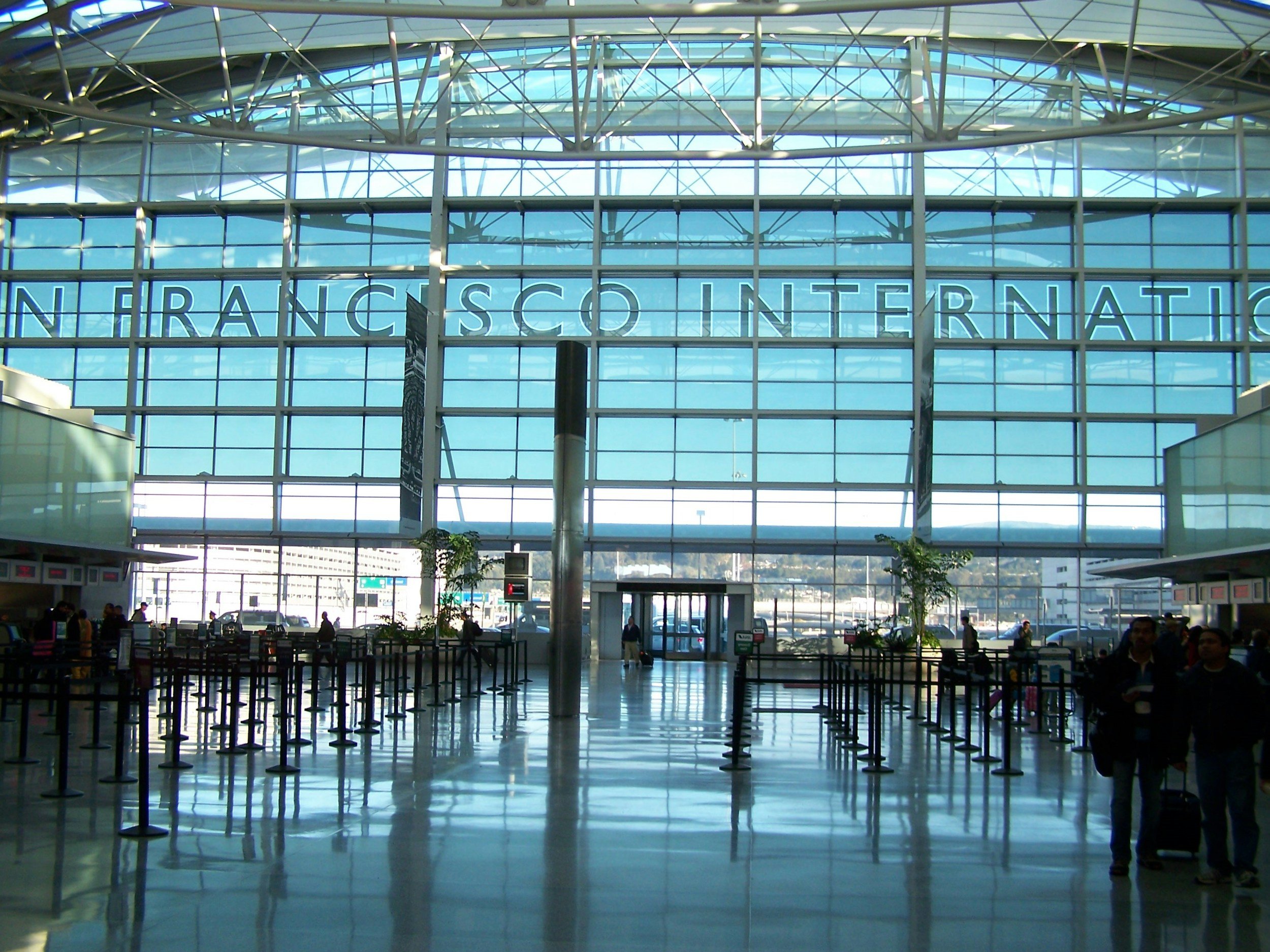 Interior of San Francisco International Airport with a large glass window and digital sign.