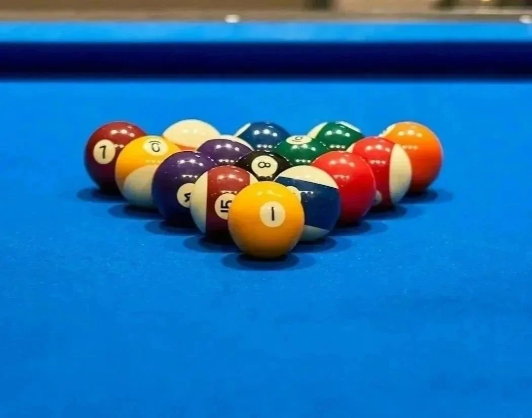 Pool balls arranged in a triangle formation on a blue billiard table.