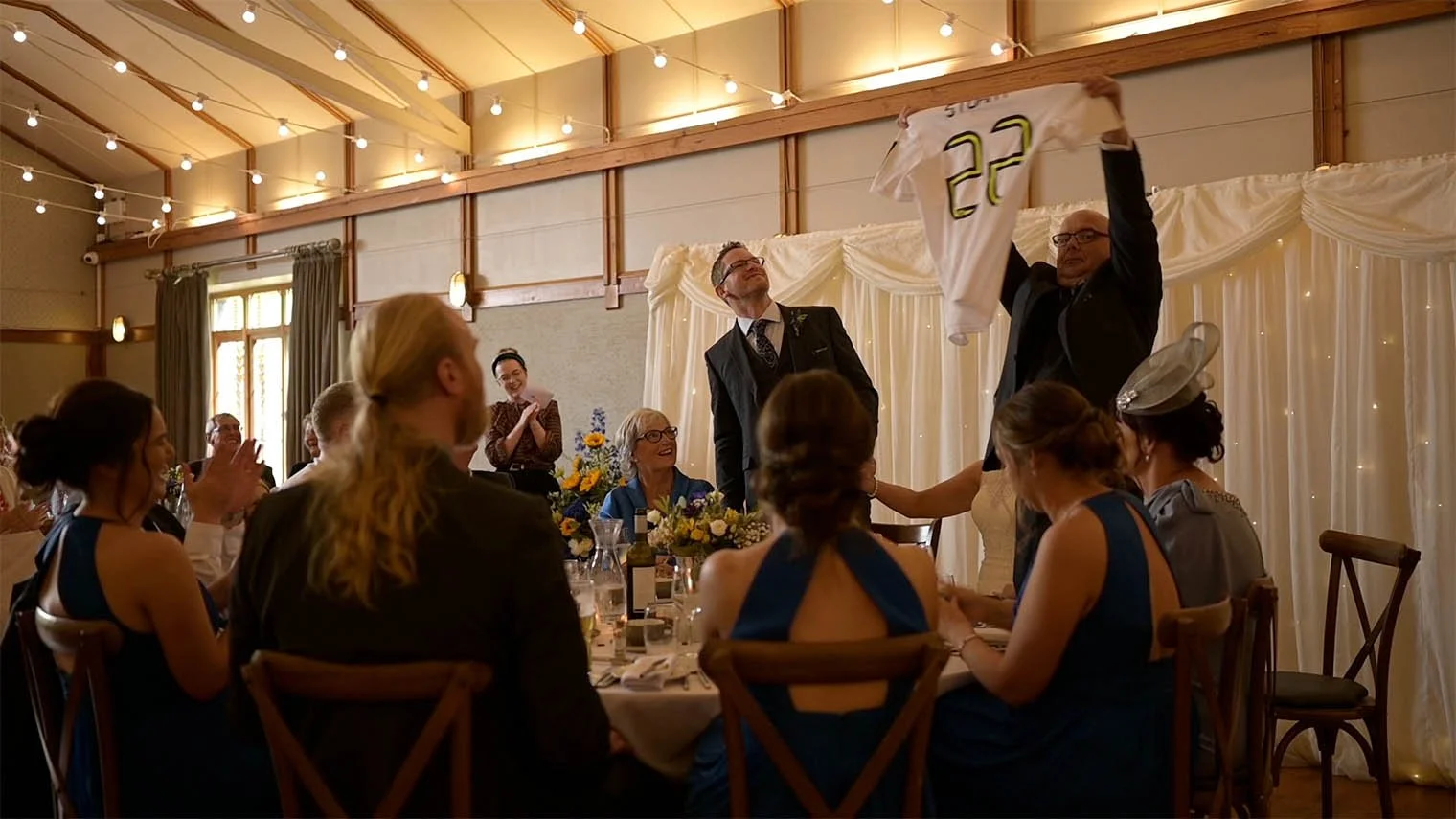 The bride’s father holds up a football shirt as he pokes fun at the groom.
