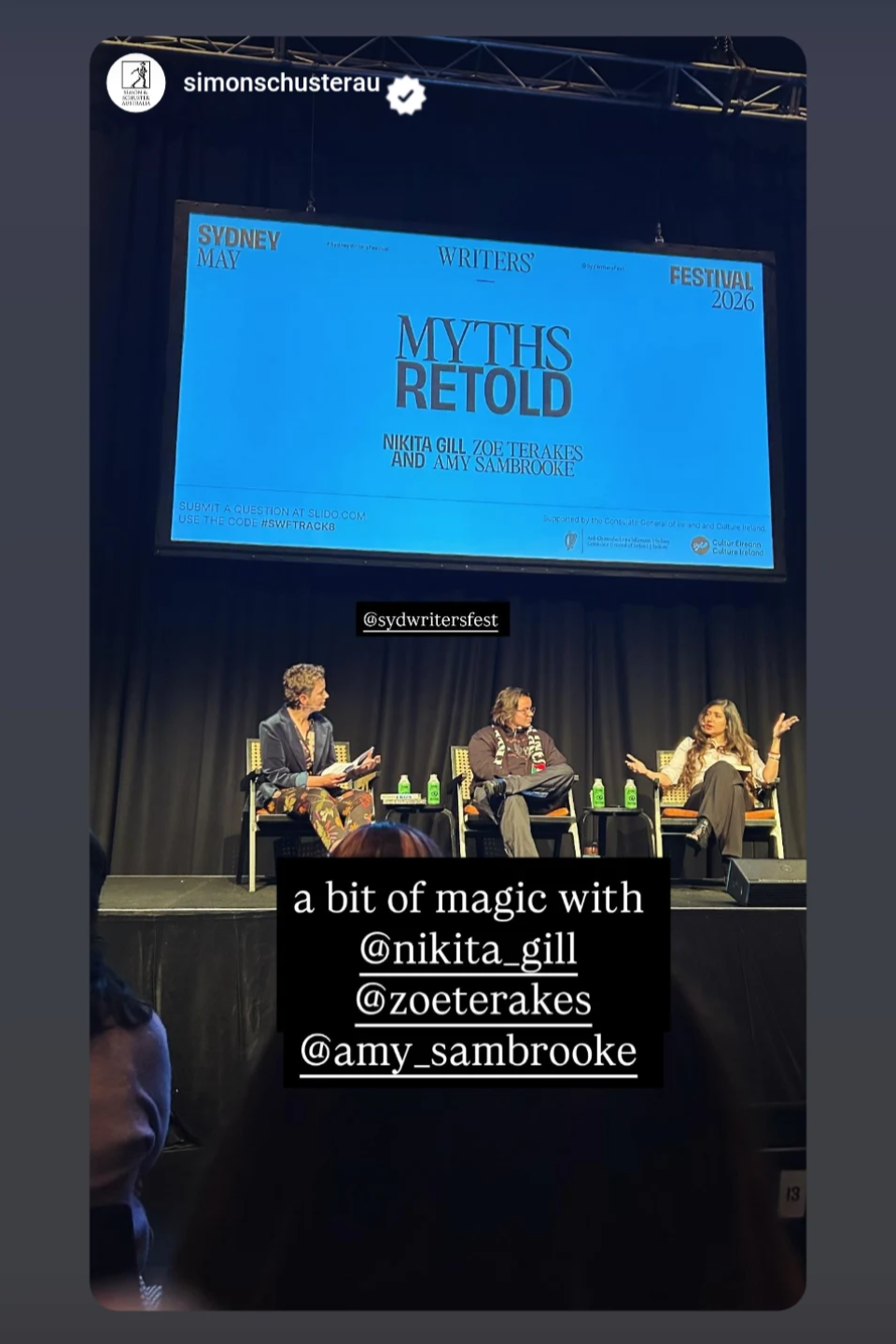 A panel discussion at the Sydney Writers' Festival 2026 with three women on stage, one speaking and two listening, seated in chairs with bottles of water in front of them. The backdrop features a large screen displaying the event's title, 'Myths Reto