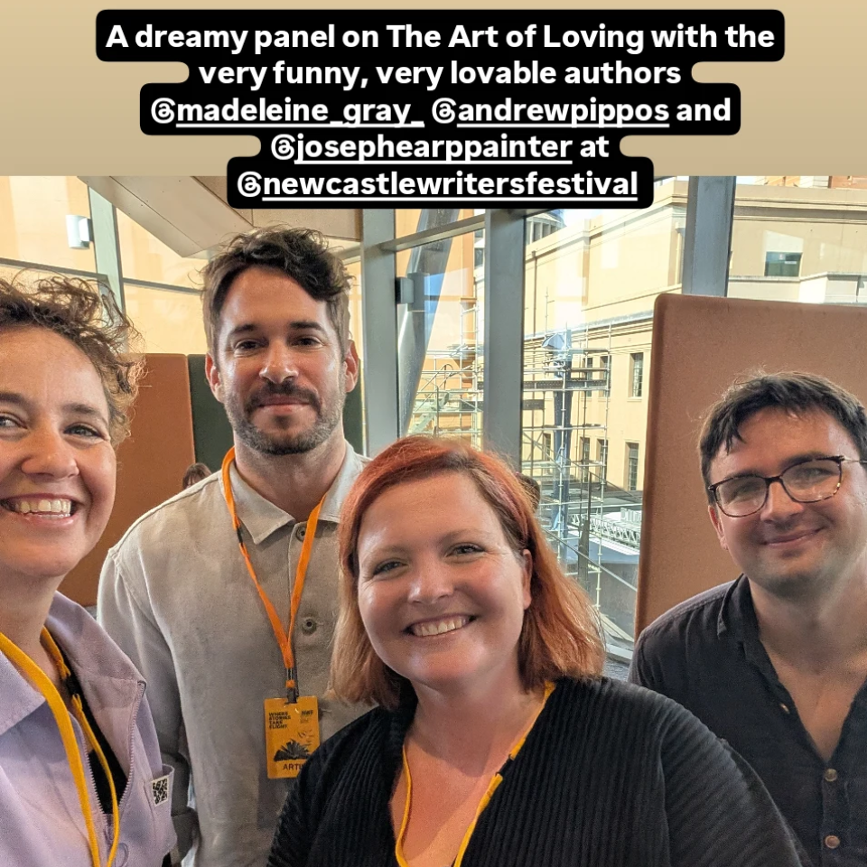 Four smiling individuals at the Newcastle Writers Festival, with a background of indoor glass walls and city buildings visible outside.