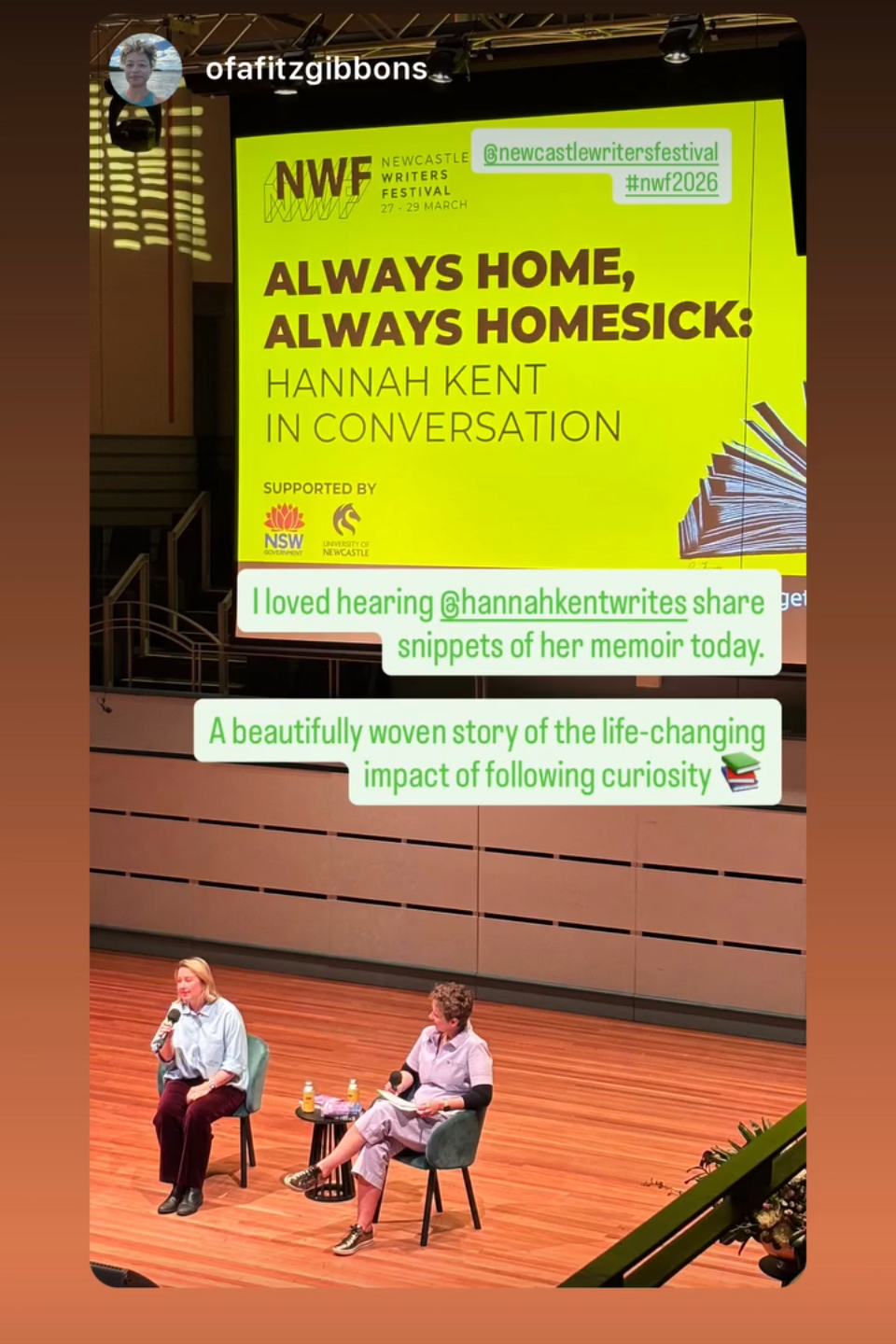 Two women sitting on chairs on a stage during a moderated conversation at the Newcastle Writers Festival, with a large bright yellow screen behind them displaying event details and positive audience feedback.