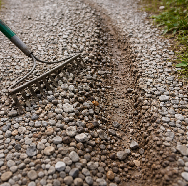 gloved hands tamping gravel driveway rut