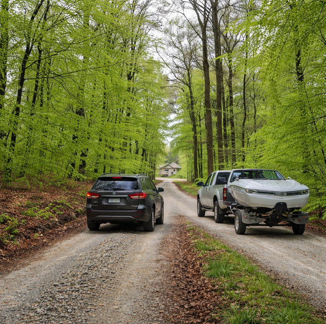 gravel rural driveway with passing vehicle and parked boat trailer