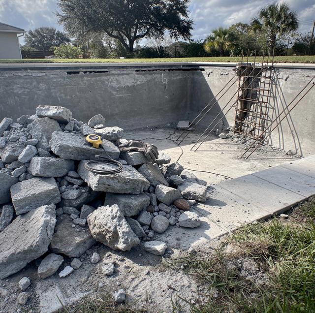 demolition crew breaking concrete pool shell with jackhammer