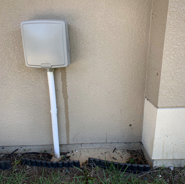 technician inspecting sprinkler pump beside suburban house