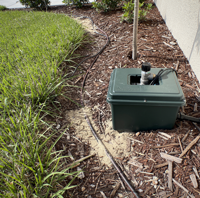 sprinkler head barely spraying dry grass in backyard