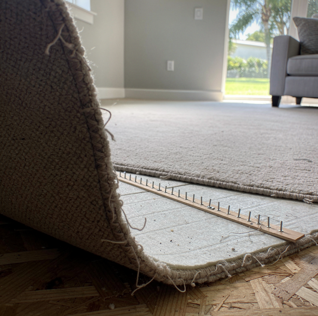 construction worker peeling glued carpet from concrete floor