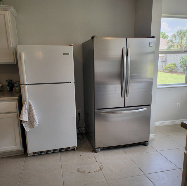 delivery crew carrying old refrigerator out of kitchen