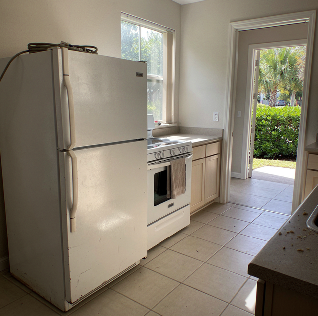 man hauling old washing machine out of kitchen doorway