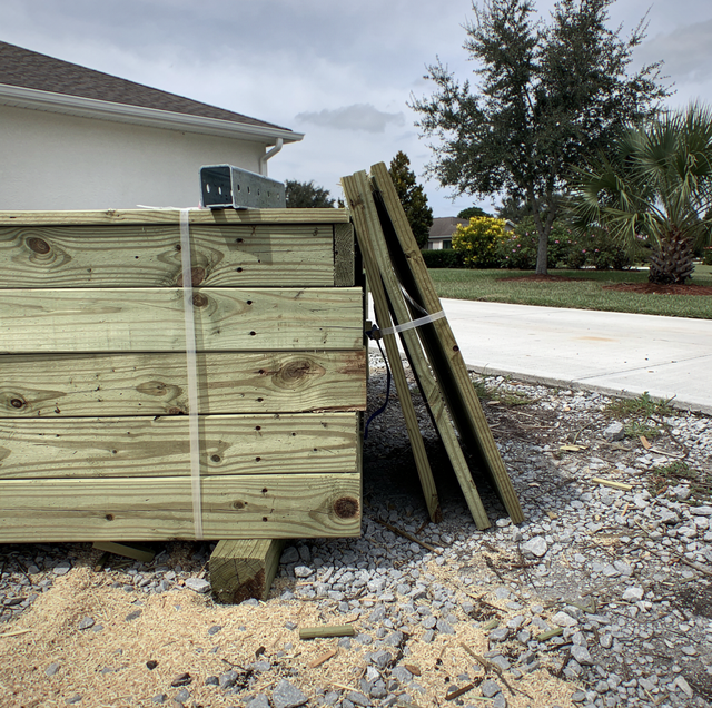 stacked pressure-treated deck boards loaded into dump trailer