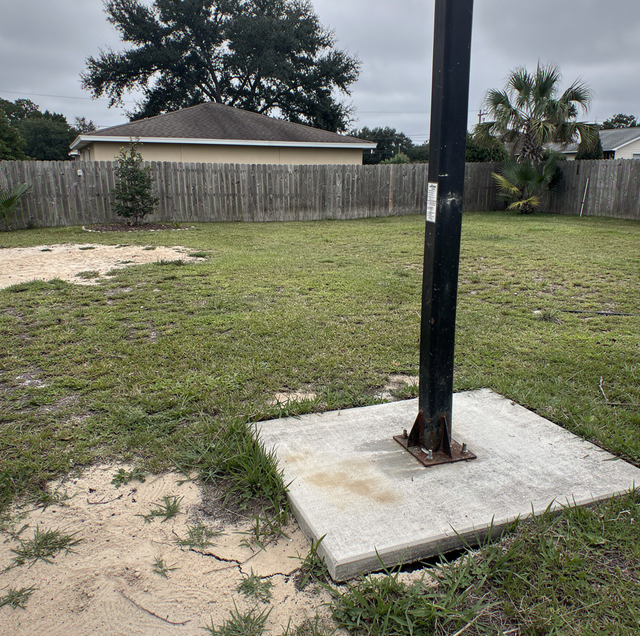 cracked backyard basketball slab with exposed goal footing