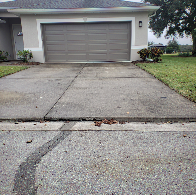 cracked concrete driveway apron beside curb line