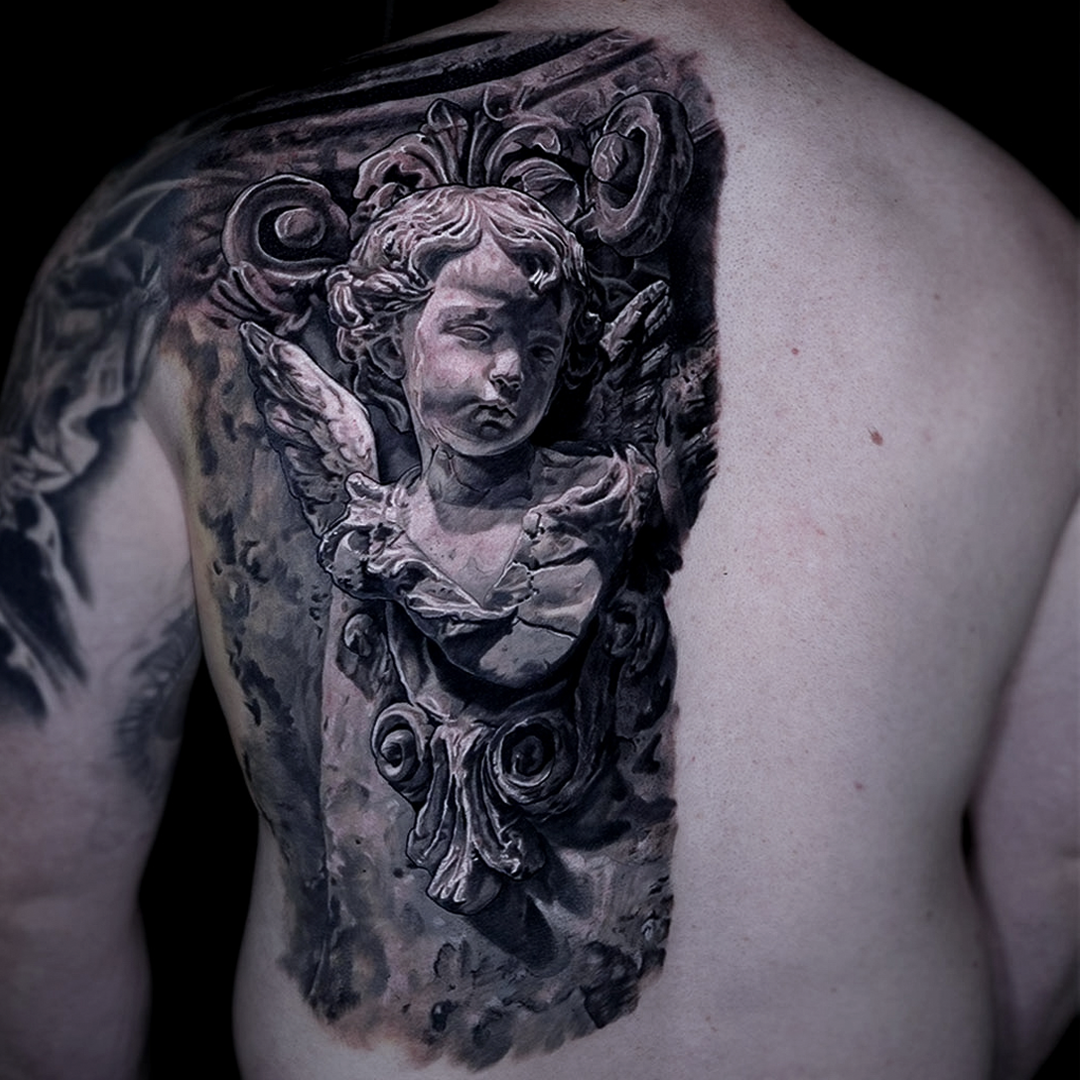 Large scale back tattoo by Glen Middleton featuring a baroque cherub sculpture in black and grey realism.