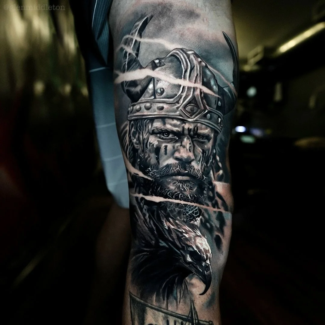 Large scale black and grey tattoo by Glen Middleton featuring a Viking warrior in battle with a horned helmet, eagle skull headdress and dramatic realism.