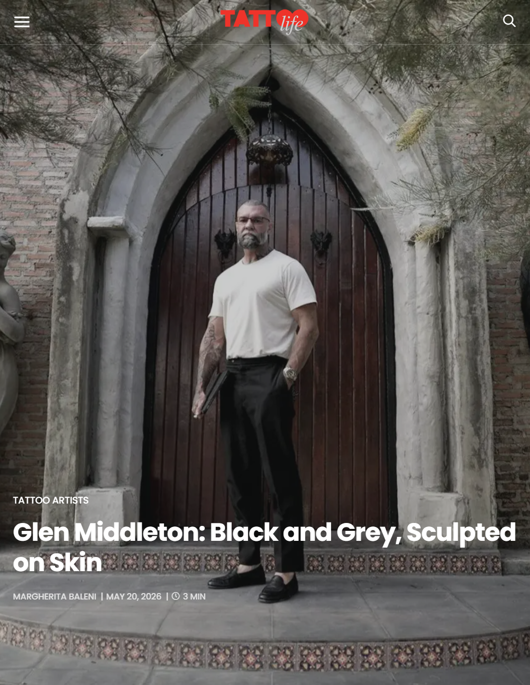Portrait of tattoo artist Glen Middleton featured in Tattoo Life magazine outside a Gothic stone doorway.