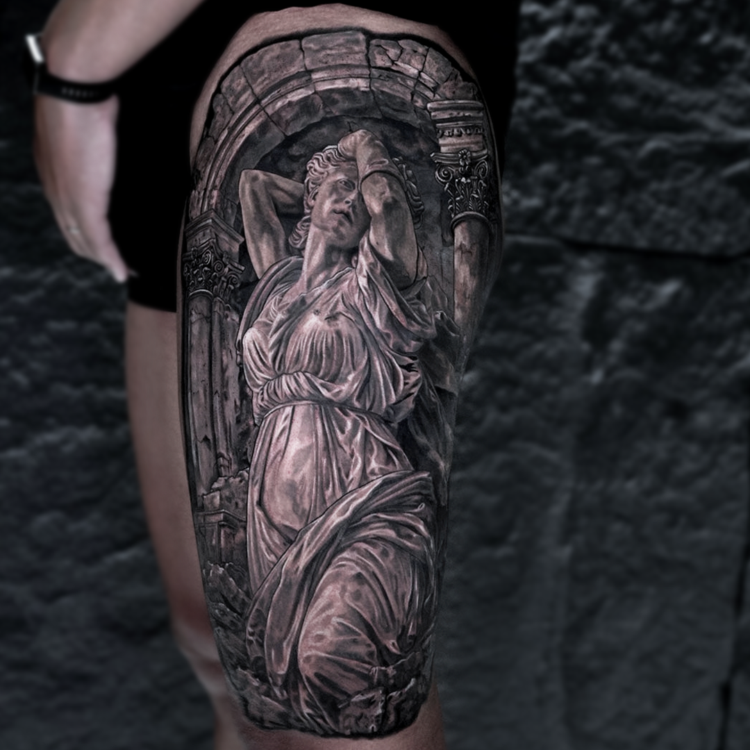 Large scale leg tattoo by Glen Middleton featuring a classical caryatid sculpture framed by Roman architecture in black and grey realism.