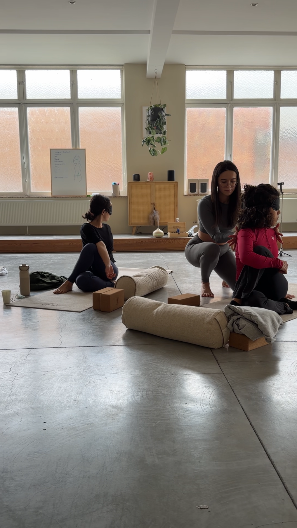 A yoga instructor offering a gentle hands-on alignment adjustment to a participant in a seated twist pose at a wellness retreat.