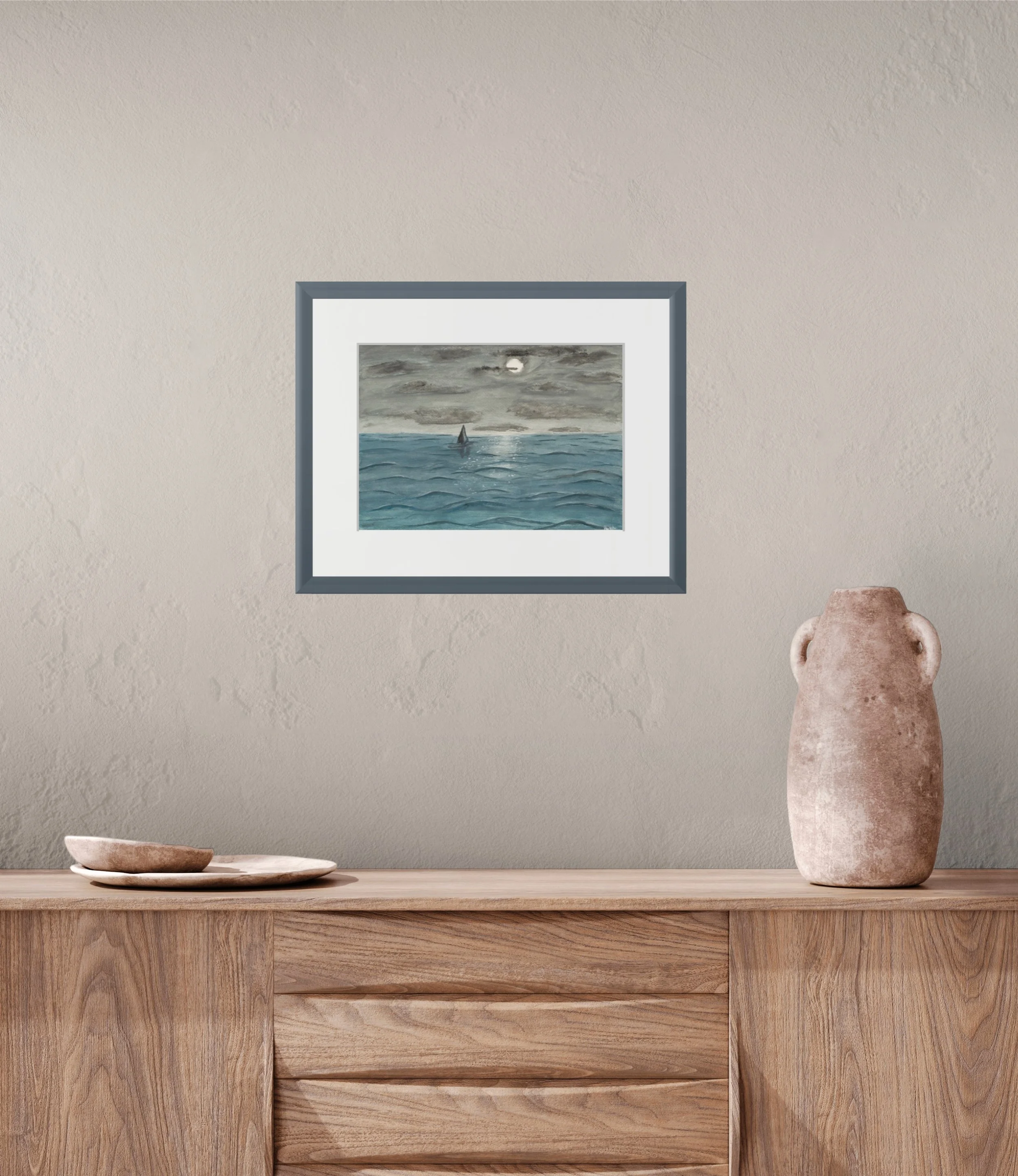 Wooden dresser with a framed painting of a seascape, a stone vase, and a bowl and plate on a wooden surface.