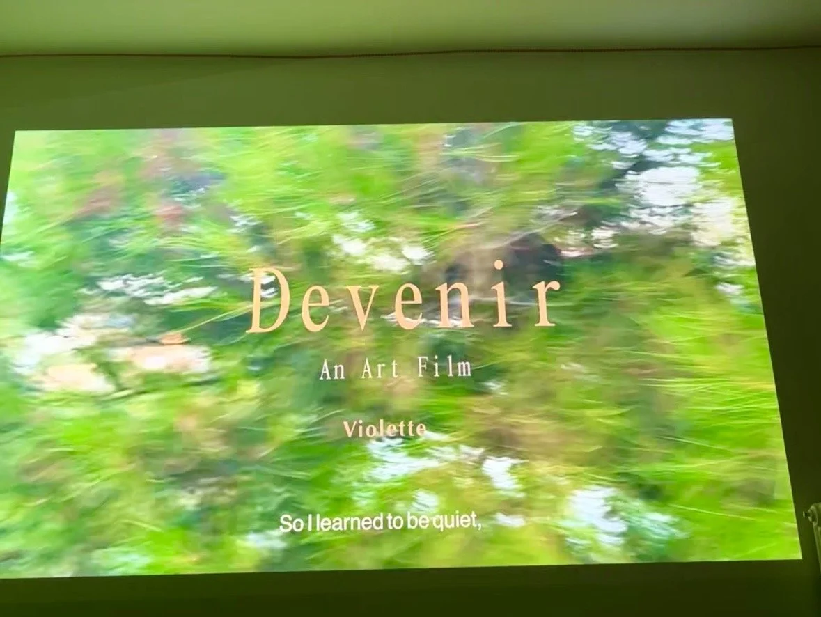 Screen displaying the title slide of an art film called "Devenir" by Violette, with a blurred green foliage background and a subtitle that reads "So I learned to be quiet."