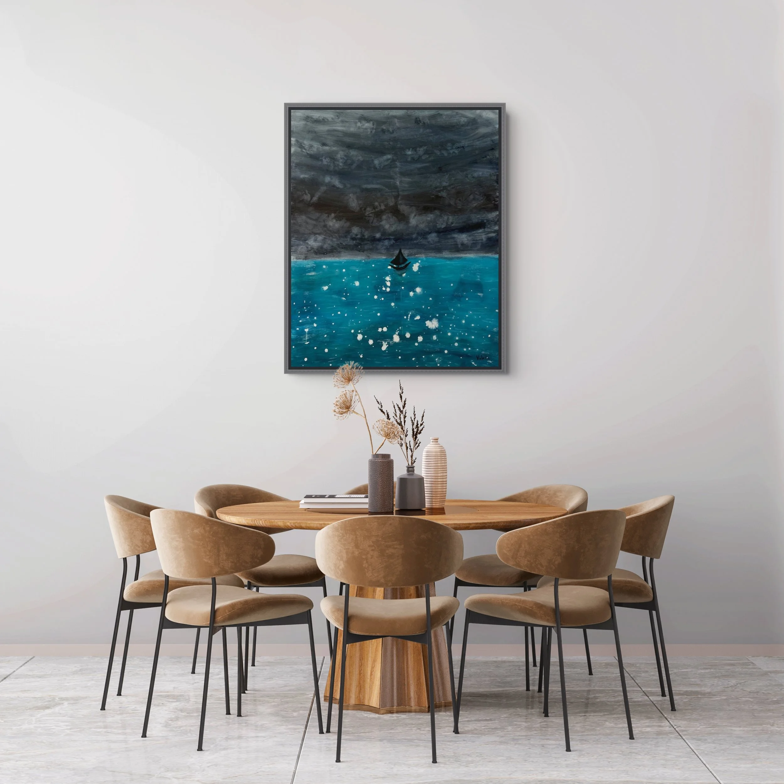 A round wooden dining table surrounded by seven beige upholstered chairs with black metal legs, set against a white wall with a framed painting of a stormy ocean scene featuring a small sailboat, and decorative vases with dried plants on the table.