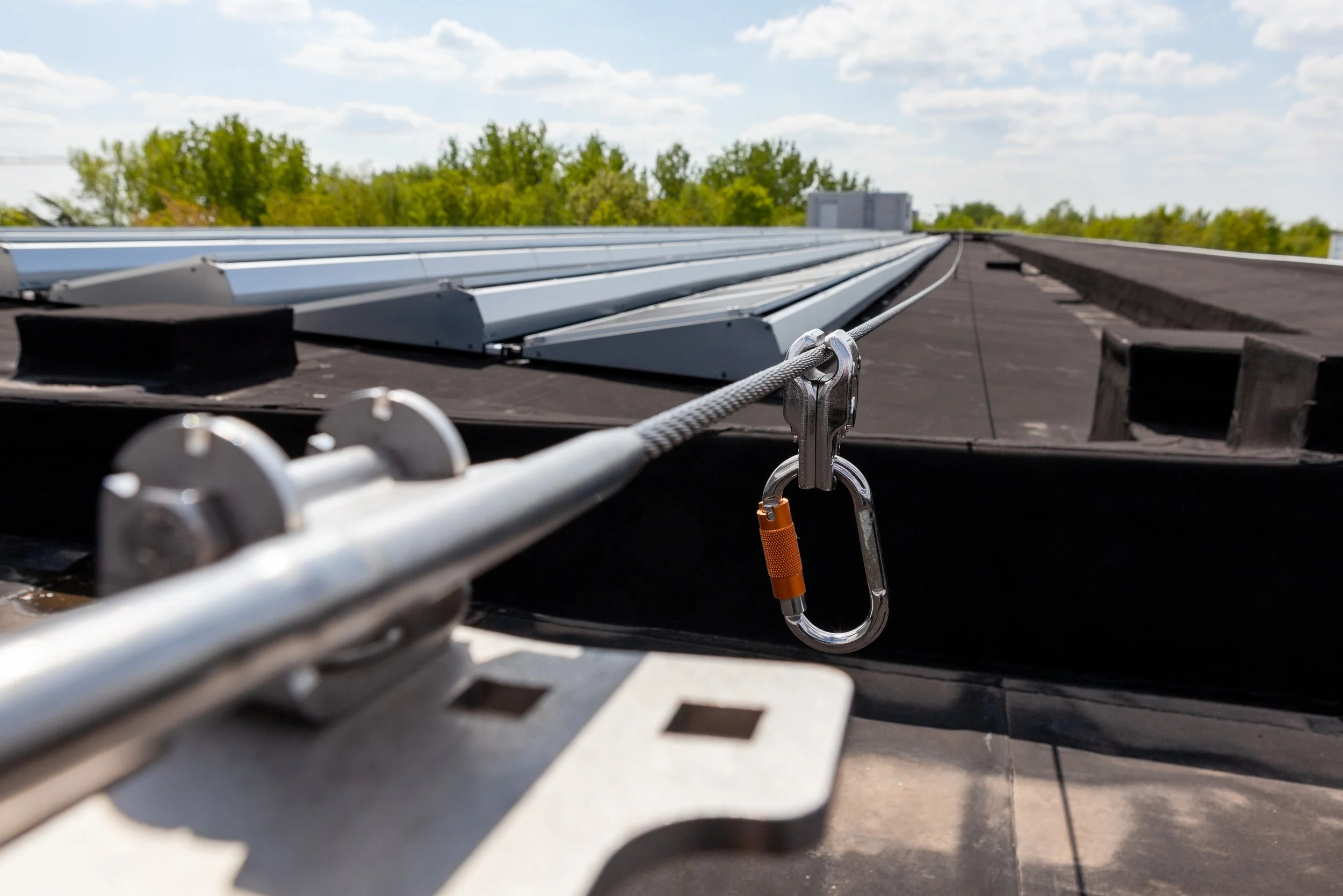 Solar panels installed on a rooftop with blue sky and trees in the background.