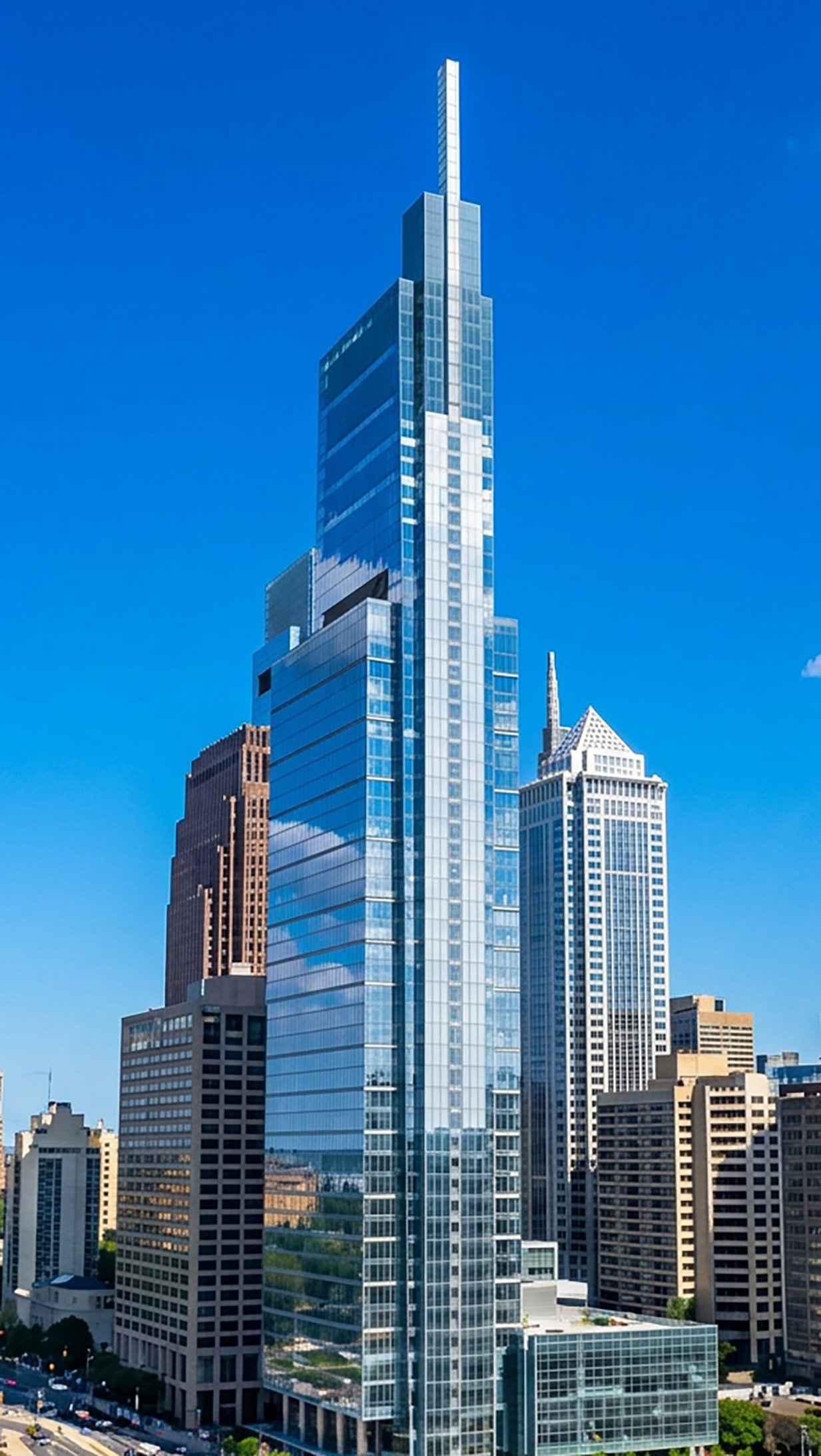 Tall modern skyscraper with glass facade in downtown Chicago, with other high-rise buildings under a blue sky.