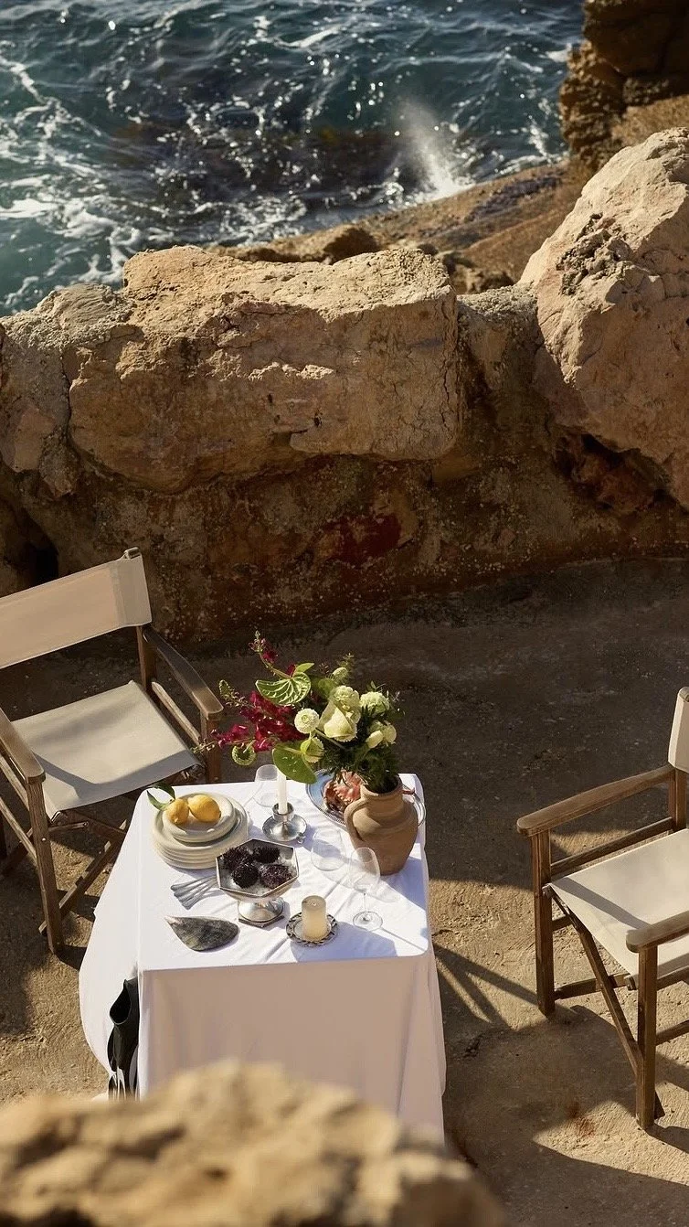 A private table for two set on a clifftop terrace above the sea