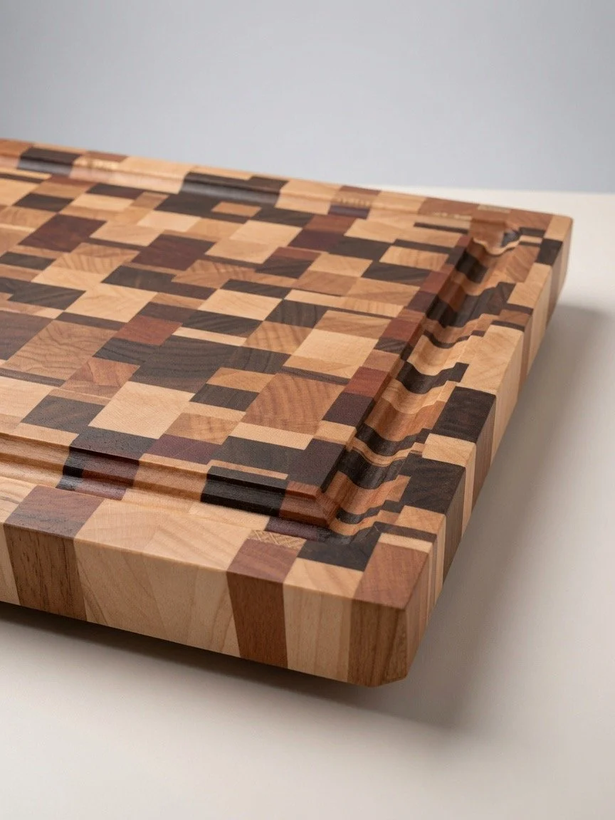 Close-up of a wooden cutting board with a geometric pattern of various wood types and colors, placed on a white surface.