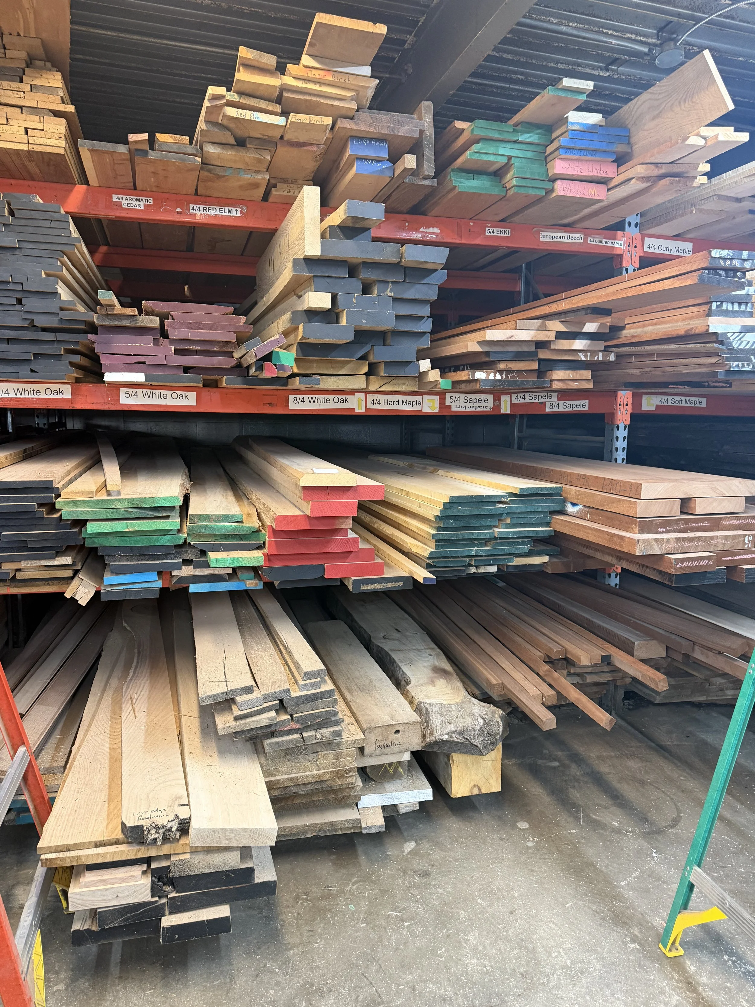 Stacks of various types of wood planks and boards stored on metal shelves in a hardware store or lumber yard