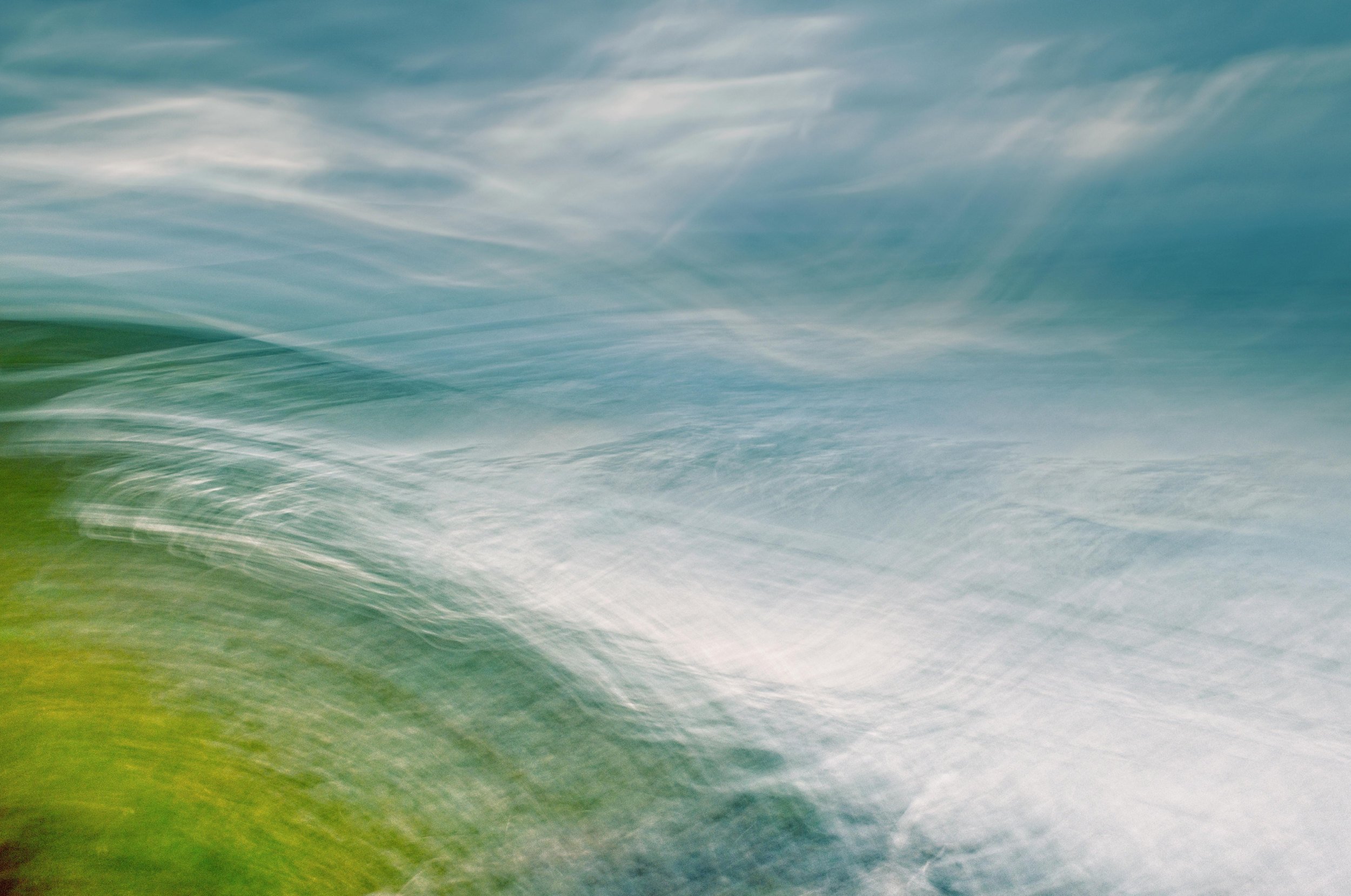 Abstract image with green, blue, and white swirling colors in motion.