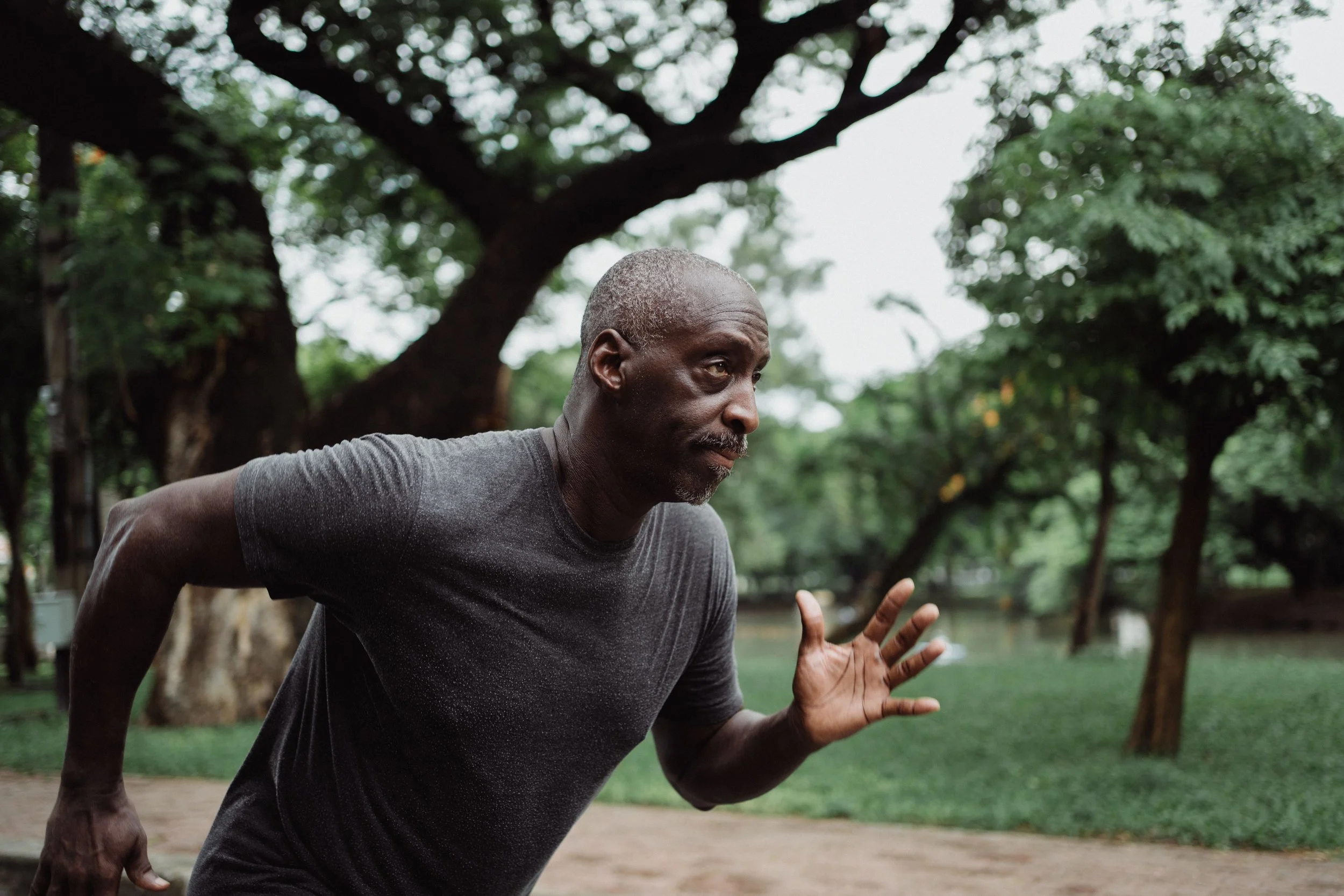 An older man exercising outdoors in a park.