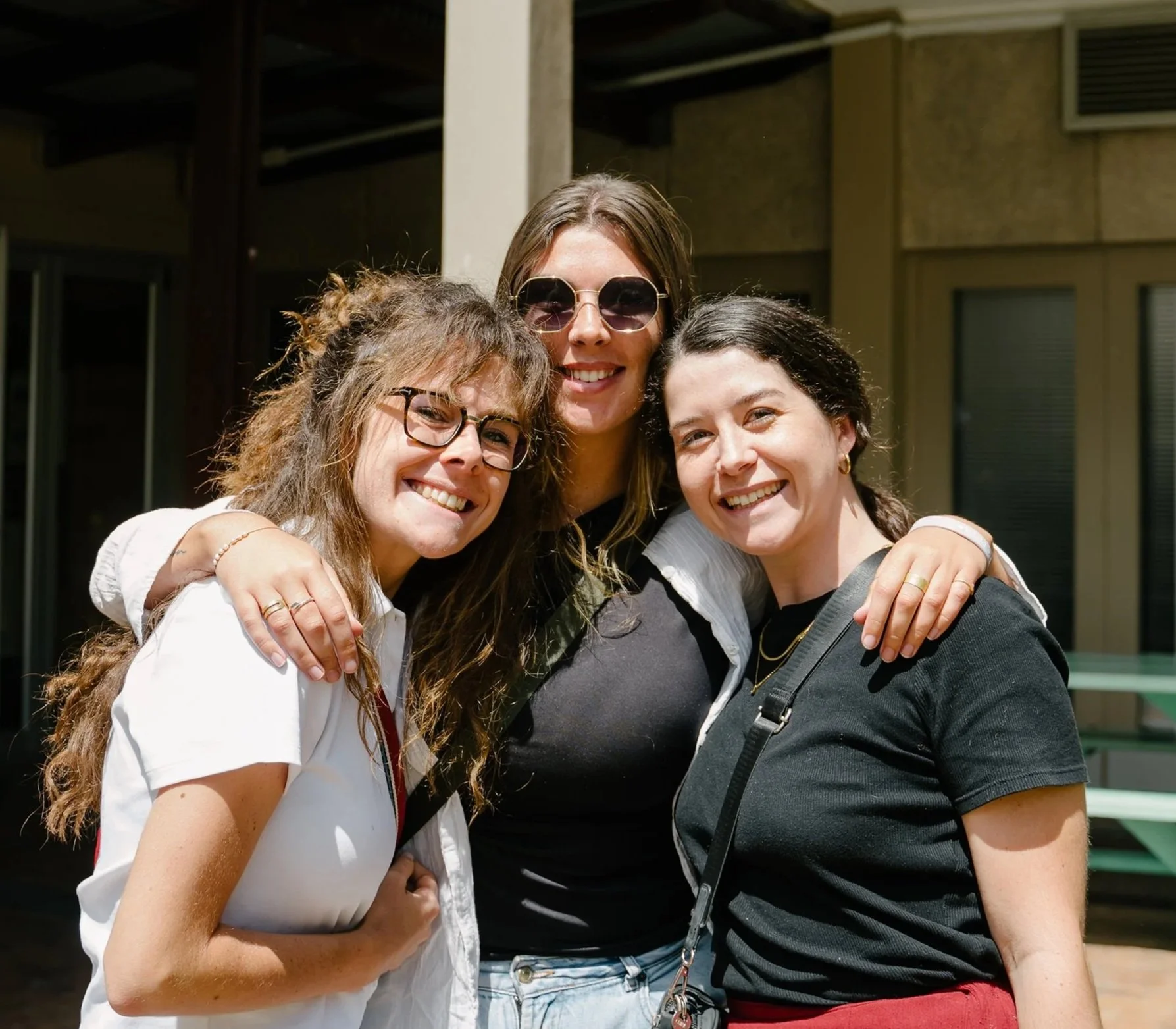 Three women standing close together and smiling