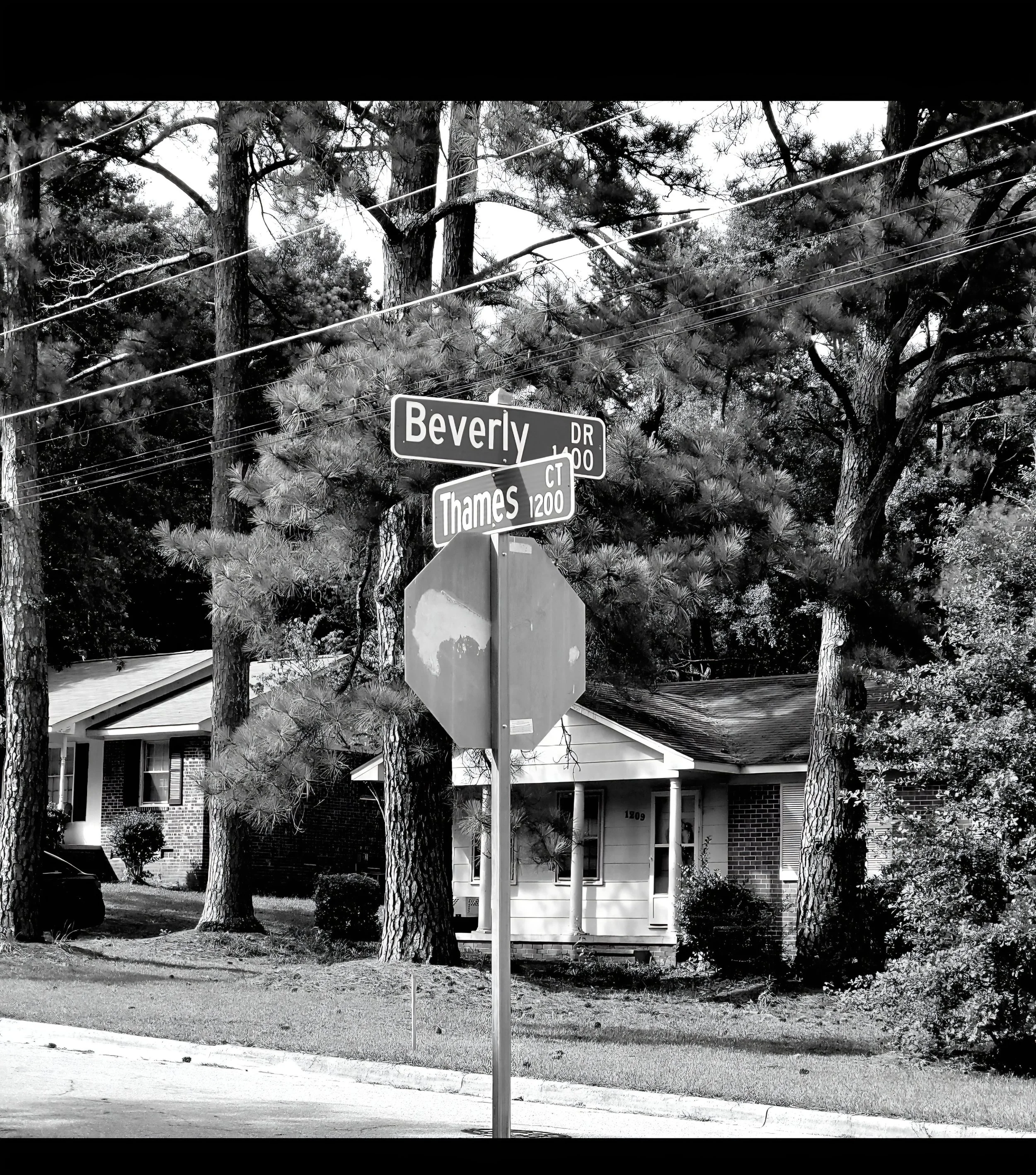 Street sign at the corner of Beverly Drive and Thames Court in a neighborhood with trees and houses.