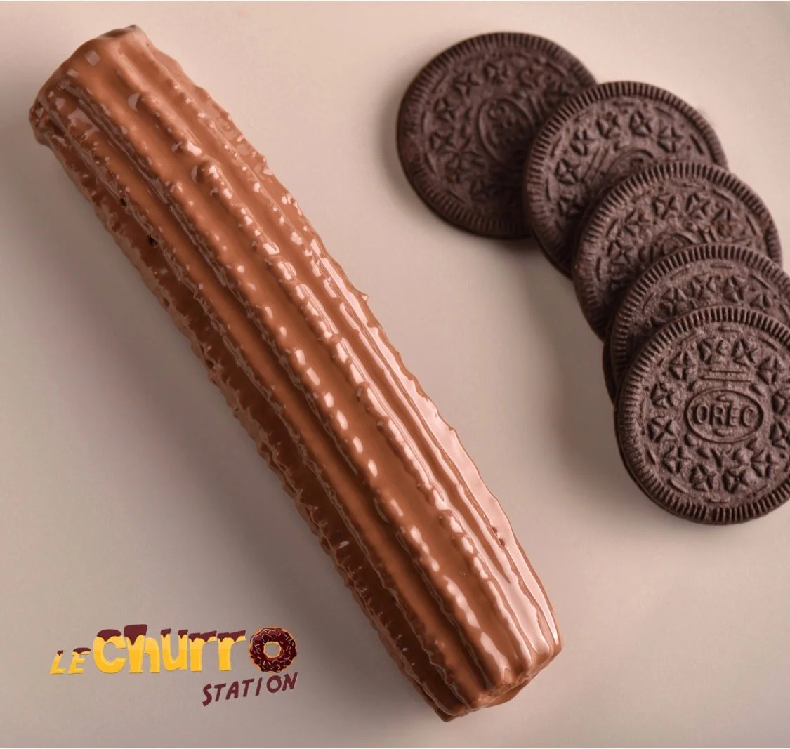 A chocolate éclair and a row of Oreo cookies on a light-colored surface, with the text "Le Chutto Station" in the bottom left corner.